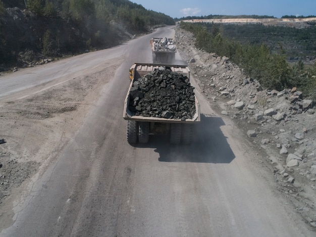 石の採石場にある巨大な産業用ダンプトラックは、道路上のドローンから運ばれた大理石または花崗岩を輸送