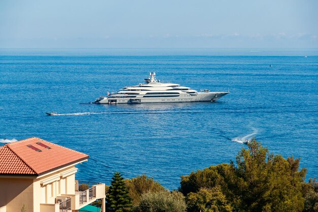 The huge mega yacht is moored in sea off the coast of the azur coastline at sunny day the chrome pla