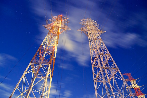 Huge metallic pylons against night windy sky