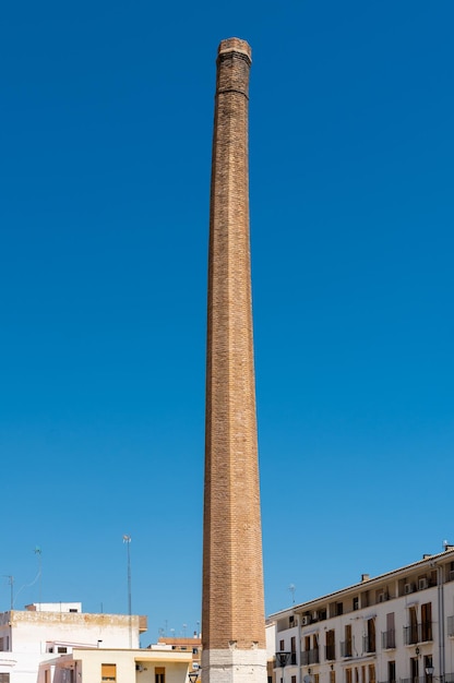 Huge old industrial chimney in brick of an old factory on blue sky background