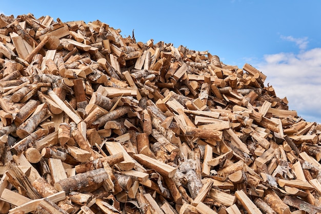 Huge pile of firewood chocks against the sky close-up