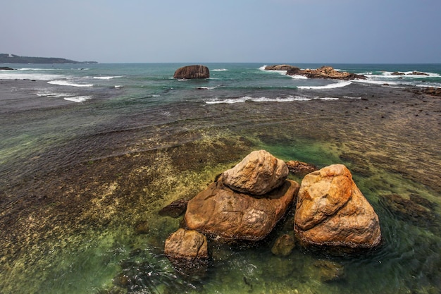 Enormi rocce nel mare limpido vicino alla riva, con l'orizzonte in lontananza. galle, sri lanka