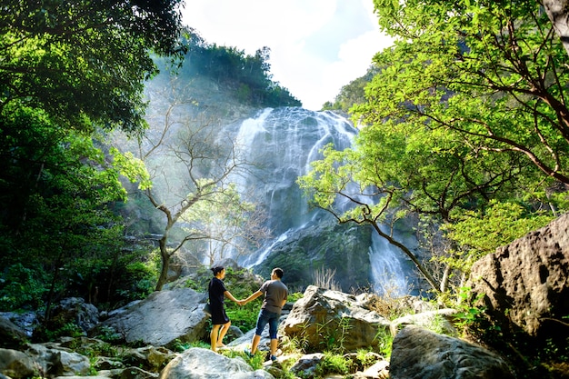 Huge waterfall with lovely couples holding each other hand 