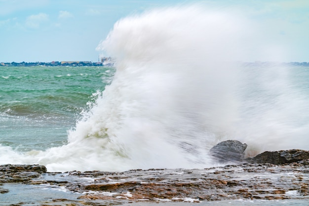 A huge wave crashes on a rocky shore