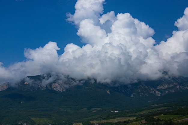 Huge white cumulus clouds over a mountain valley with vineyards in Crimea.