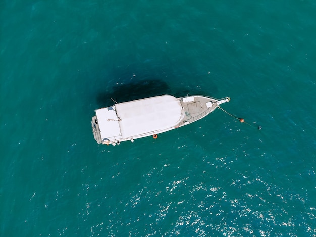 Огромная белая яхта в одиночестве плывет по глубокому синему морю, вид сверху