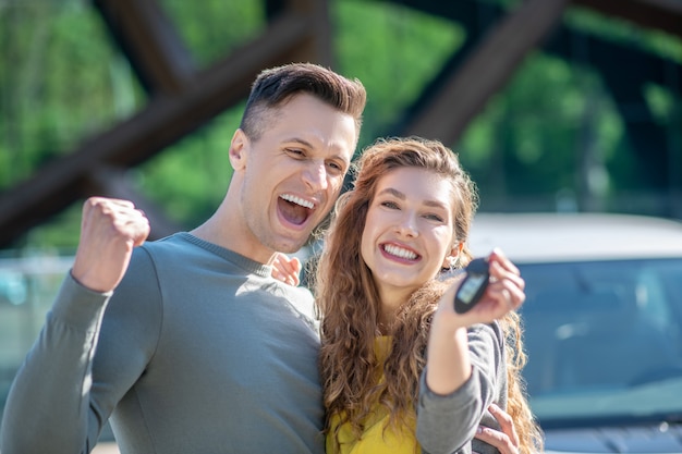 Hugged enthusiastic man and woman with a car key