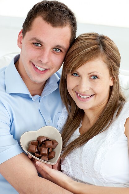 Hugging couple holding chocolote smiling at the camera 