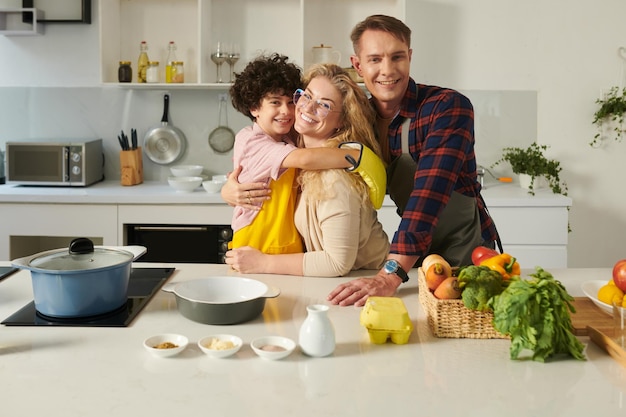 Abbracciare la famiglia in piedi in cucina