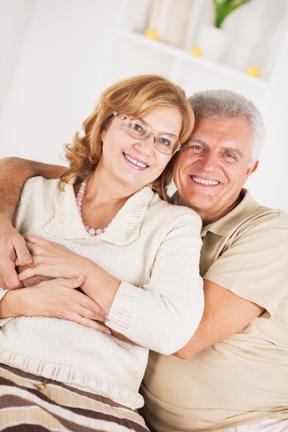 Hugging Senior couple sitting in living room.