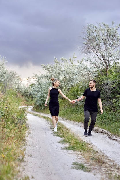 Foto abbracci e baci coppia di innamorati tra i rami dei cespugli. cammina lungo la strada, un uomo che bacia una donna. amore, affetto, relazione, emozioni vivide sul viso. coppia di innamorati orientali