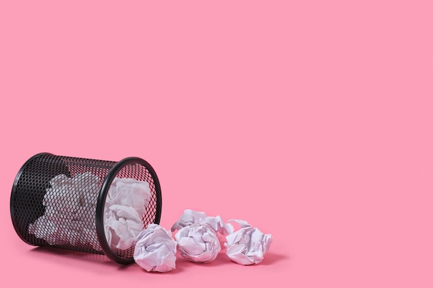 Huiduitslag van verfrommeld papier uit de prullenbak, op roze achtergrond.
