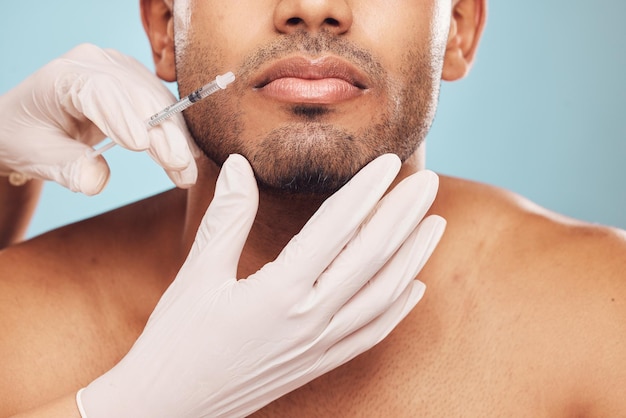 Huidverzorging botox en mond met een man in studio op een grijze achtergrond voor een plastische chirurgie injectie Handen schoonheid en spuit met een jonge mannelijke persoon binnen voor een anti-aging gezichtsvuller close-up