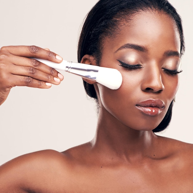 Huidverzorging make-up en zwarte vrouw met penseel op gezicht in studio met cosmetische toepassingstool Huidverzorging blozen en gezichtscosmetica model met luxe contour schoonheid op witte achtergrond met mockup