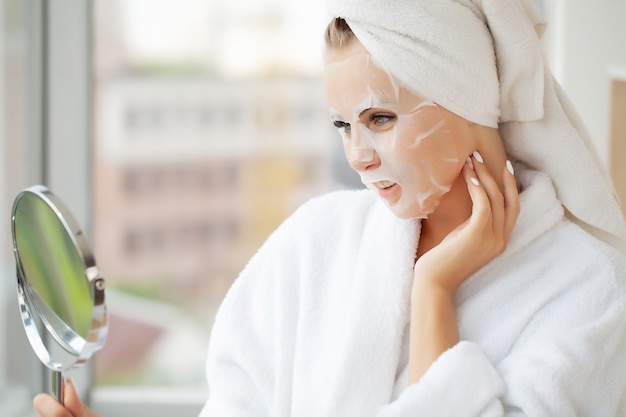Huidverzorging, mooie vrouw met gezichtsmasker bij schoonheidssalon.