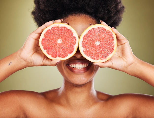 Huidverzorging wellness en zwarte vrouw met grapefruit en glimlach in de studio voor een gezonde levensstijl Schoonheid creatief en gelukkig meisje met fruit over de ogen marketing van biologische natuurlijke en verse schoonheidsproducten