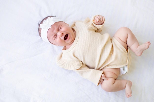 Huilend pasgeboren babymeisje in een wieg thuis op een wit katoenen bed thuis