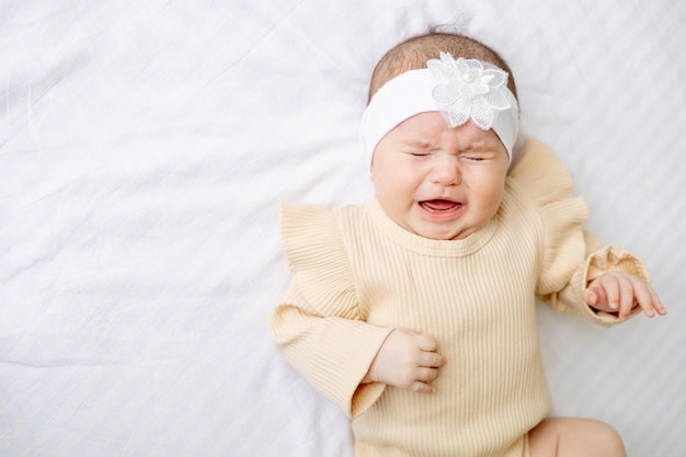 Huilend pasgeboren babymeisje in een wieg thuis op een wit katoenen bed thuis