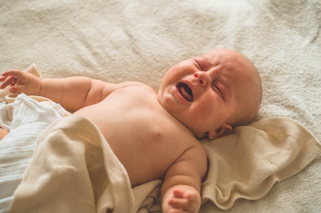 Huilende baby liggend op het bed