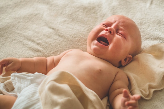 Huilende baby liggend op het bed