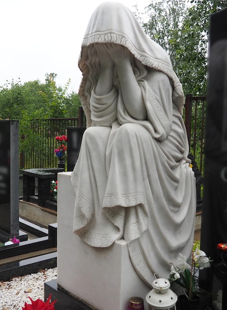 Huilende vrouw sculptuur op de begraafplaats de figuur van een moeder vrouw of vrouw in een kap of stal kreupel