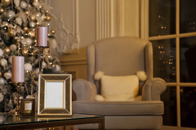 Huis gezellige kerst en gelukkig nieuwjaar interieur in woonkamer met kerstboom, een fauteuil en frame om op tafel te schrijven. Achtergrond in vintage avondstijl met kopieerruimte. Concept van vieren