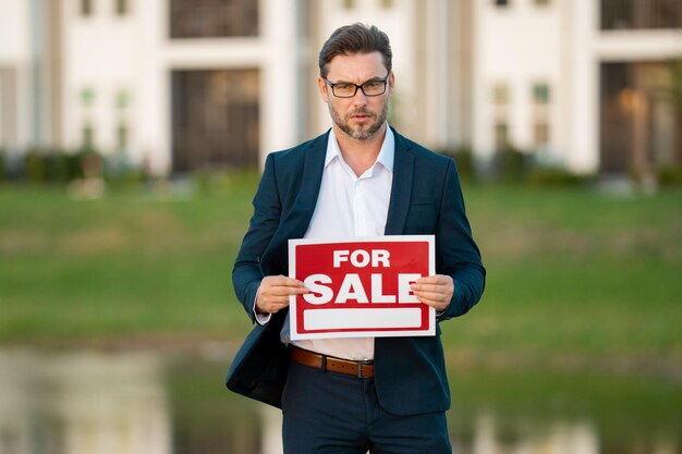 Foto huis te koop concept voor aankoop en verkoop van onroerend goed onroerend goeddiensten zelfverzekerde zakenman in pak makelaar professionele makelaar die nieuwe woning aanbiedt onroerendgoed huis aan koper