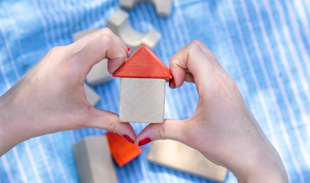 huis van houten kubussen in de hand van de vrouw rode kleur nagel blauwe deken en nog een eco-speelgoed in backgr