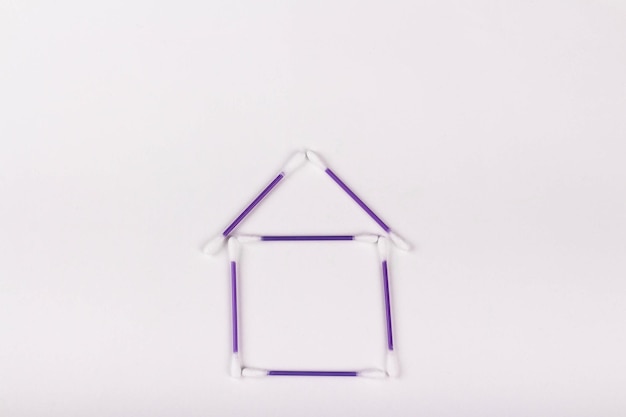 Huis van paarse wattenstaafjes op een witte achtergrond kopie ruimte