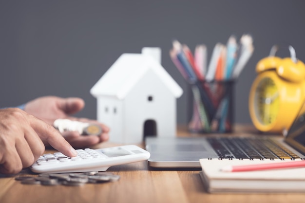 Foto huisaankoop en kostenidee huisrente berekenen concept man gebruikt rekenmachine op bureau om het aantal geld voor huisfinanciën te plannen en te vinden woningaankoopplanning