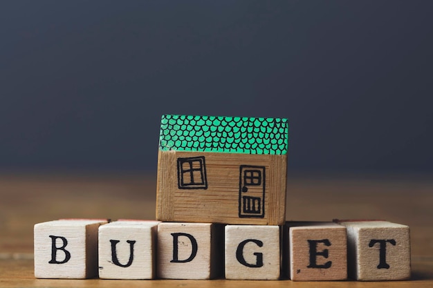 Huisbudgetconcept Huismodel met budgetwoord gemaakt van houten blokken