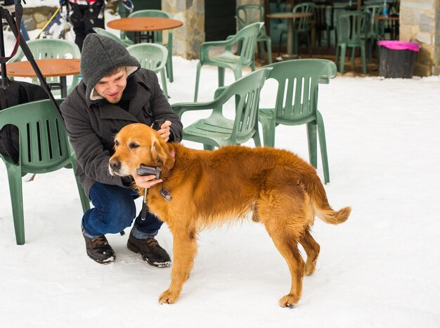 Huisdier eigenaar, hond en mensen concept - jonge lachende blanke man en hond buiten in de winter.