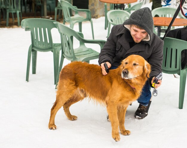 Huisdier eigenaar, hond en mensen concept - jonge lachende blanke man en hond buiten in de winter.