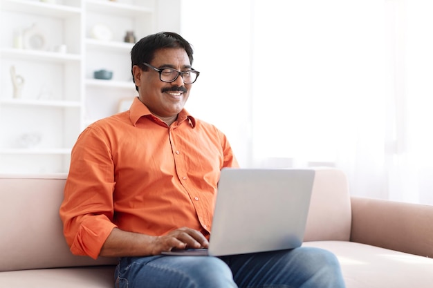 Huiselijke techsavvy Indiase man aan het werk op laptop