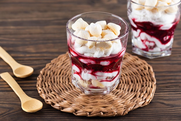 Huisgemaakt dessert met aquafaba meringue kokosroom en kersen in glazen op een houten tafel