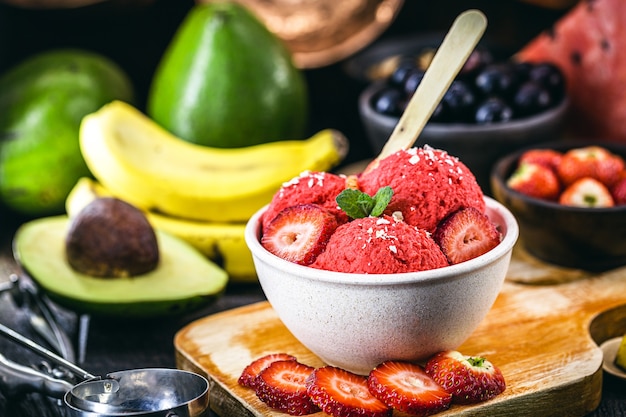 huisgemaakt en veganistisch aardbeienijs gemaakt zonder melk, met fruit op de achtergrond