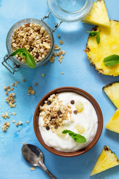 Huisgemaakt gezond ontbijt in een kom met huisgemaakte gebakken granola verse ananas en yoghurt