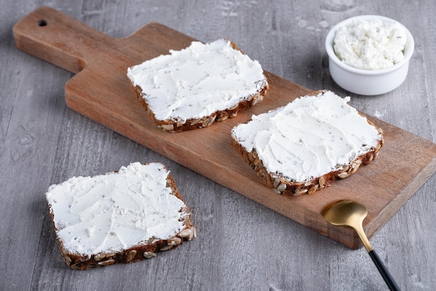 Huisgemaakt roggebrood op een houten snijplank met kwark en ricotta