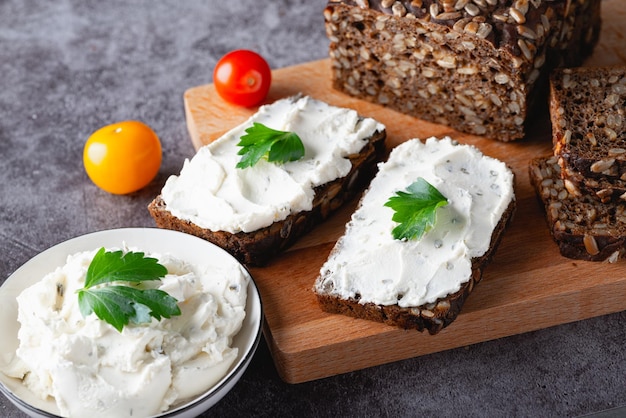 Huisgemaakt roggebrood op een houten snijplank met kwark, ricotta en kruiden