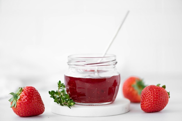 Foto huisgemaakte aardbeienjam en verse aardbeien op een witte tafel