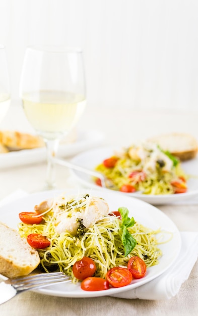 Huisgemaakte angel hair pasta met pestosaus, geroosterde cherrytomaatjes en gegrilde kip.