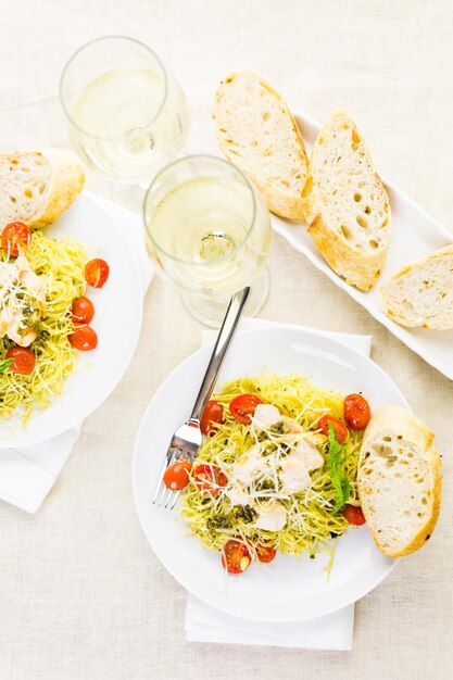 Huisgemaakte angel hair pasta met pestosaus, geroosterde cherrytomaatjes en gegrilde kip.