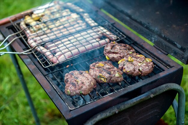 Huisgemaakte burgers op de grill met worstjes en kip