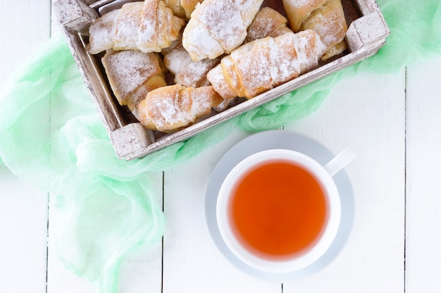 Huisgemaakte croissants met jam, versierd met poedersuiker en een kopje ochtendthee