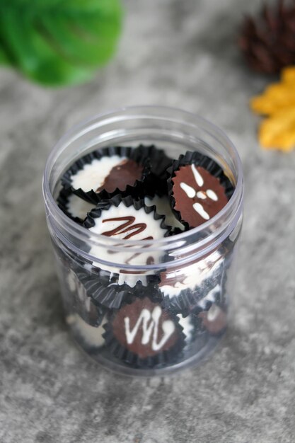 Huisgemaakte donkere chocolade en witte beker op een doorzichtige pot chocolade beker met grijze achtergrond