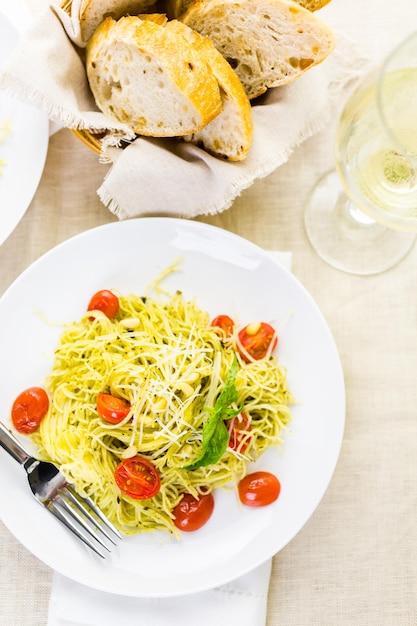 Huisgemaakte engelenhaarpasta met pestosaus en geroosterde kerstomaatjes.