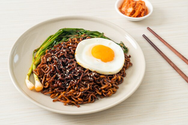 Huisgemaakte gedroogde Koreaanse pittige zwarte saus instant noedels met gebakken ei en kimchi