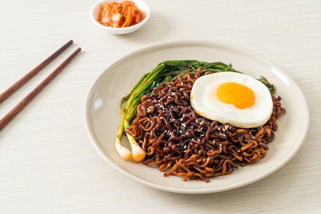 Huisgemaakte gedroogde Koreaanse pittige zwarte saus instant noedels met gebakken ei en kimchi