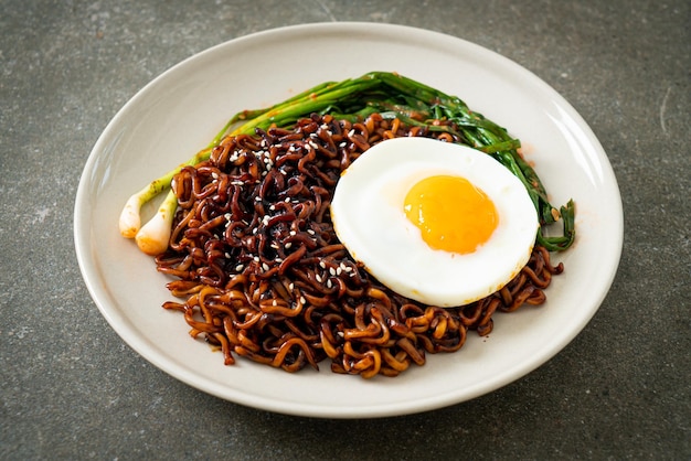 Huisgemaakte gedroogde Koreaanse pittige zwarte saus instant noedels met gebakken ei en kimchi