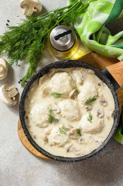 Huisgemaakte gehaktballen in zure roomsaus met champignons in een pan op stenen of leistenen tafel Bovenaanzicht